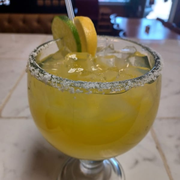 A salted-rim margarita with ice, garnished with a lime and lemon slice, at Vaqueros Mexican Restaurant.