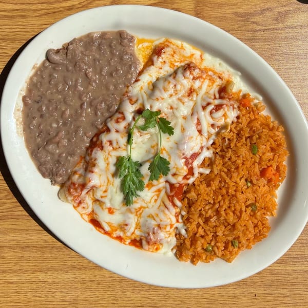 A Vaqueros Mexican Restaurant plate with cheesy enchiladas, refried beans, and Mexican rice.