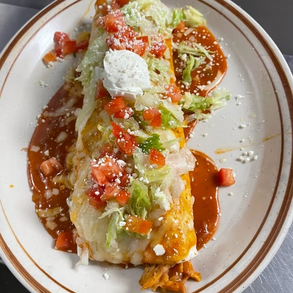 Vaqueros Mexican Restaurant's burrito, smothered in red sauce, topped with lettuce, tomatoes, and sour cream.