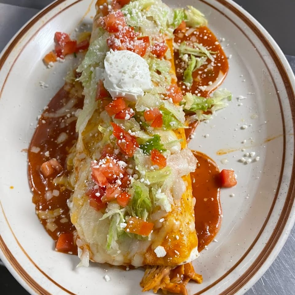 Vaqueros Mexican Restaurant's burrito, smothered in red sauce, topped with lettuce, tomatoes, and sour cream.