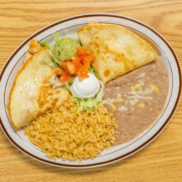 Two golden-brown quesadillas with rice, refried beans, guacamole, pico de gallo, and sour cream.